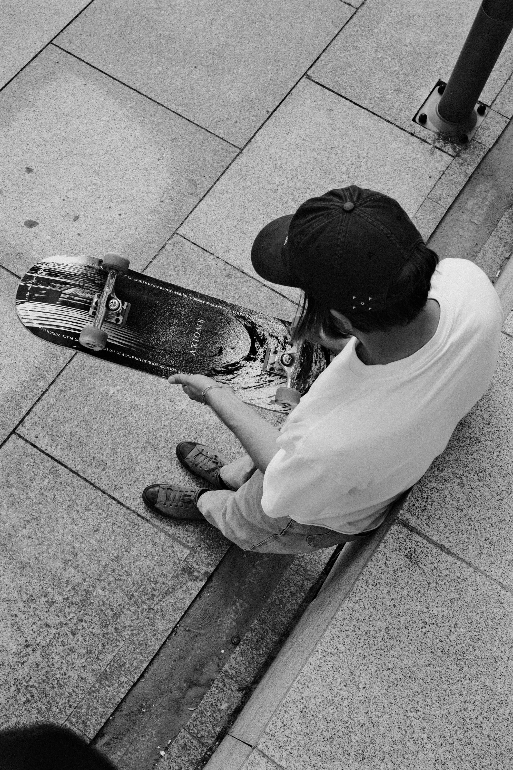 Skater sitting on a curb holding the Unpolished Form deck